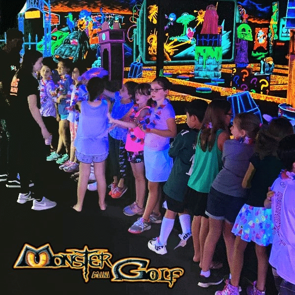 A line of kids celebrating a birthday party at monster mini golf.
